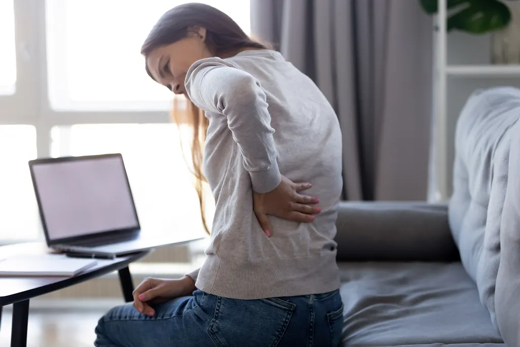 Young woman with back pain after sitting at a laptop