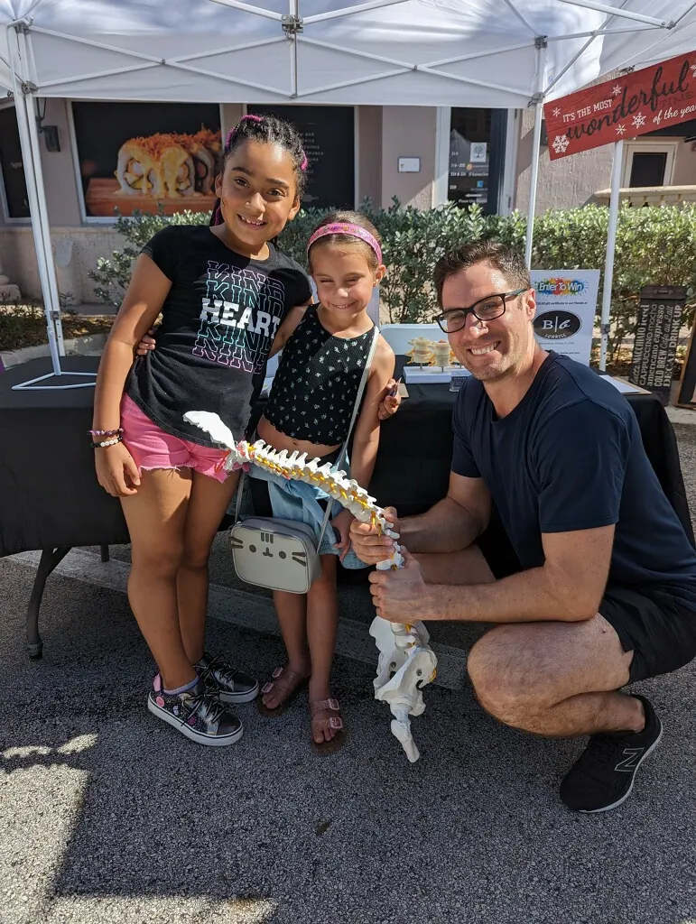 Dr. David Ridos showing children a spine model at a community event